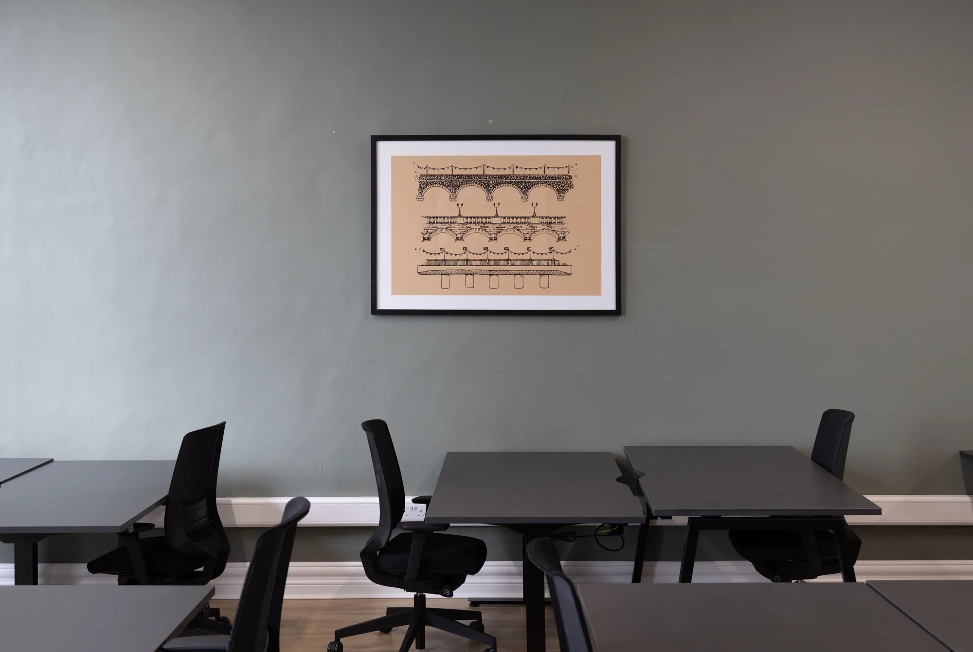 A framed architectural print above office desks