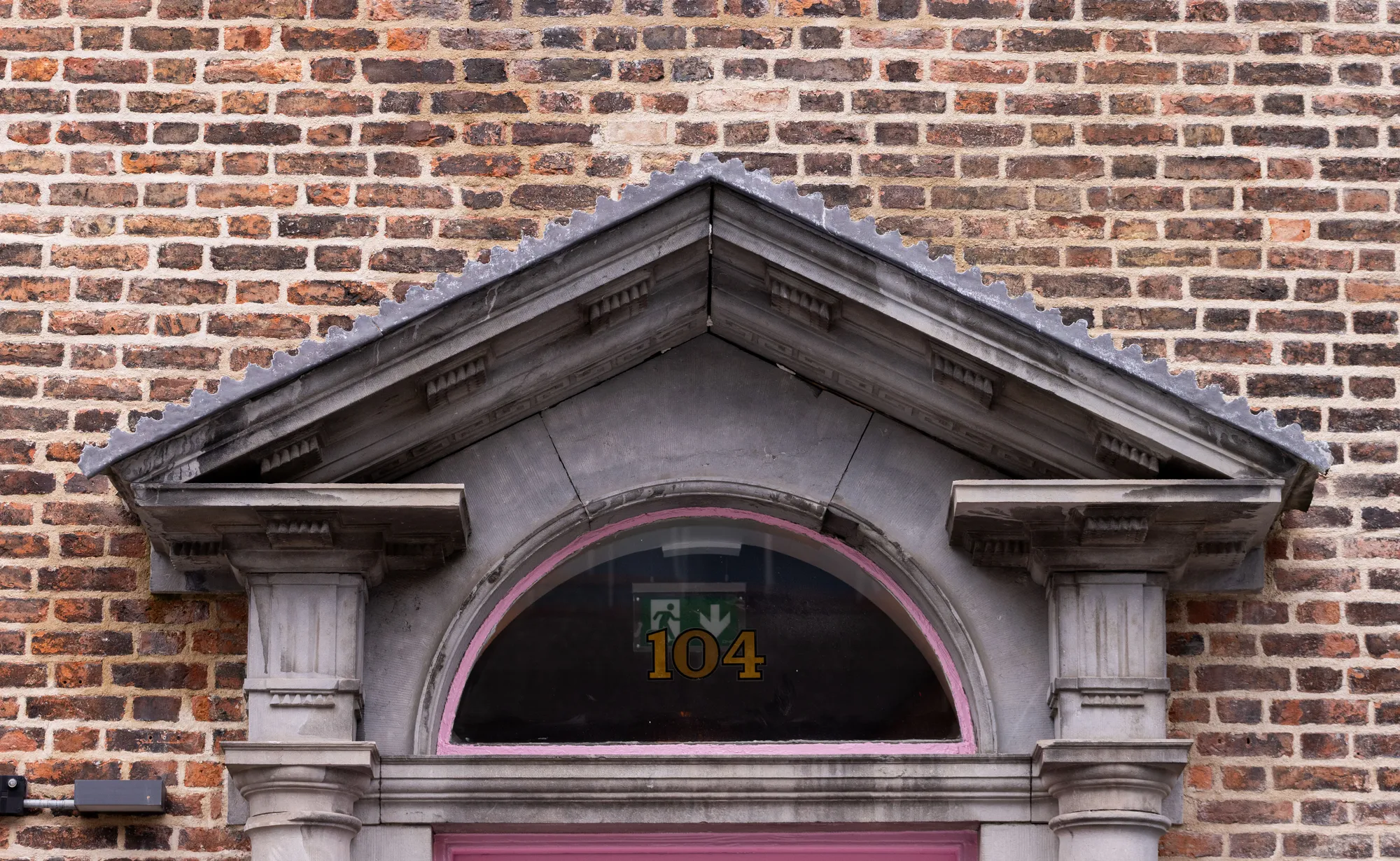 The stone pediment and fanlight above the door, numbered 104