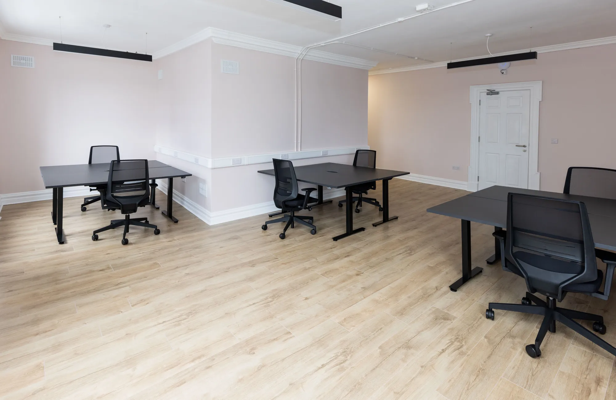 A bright private office with blush walls and four desks