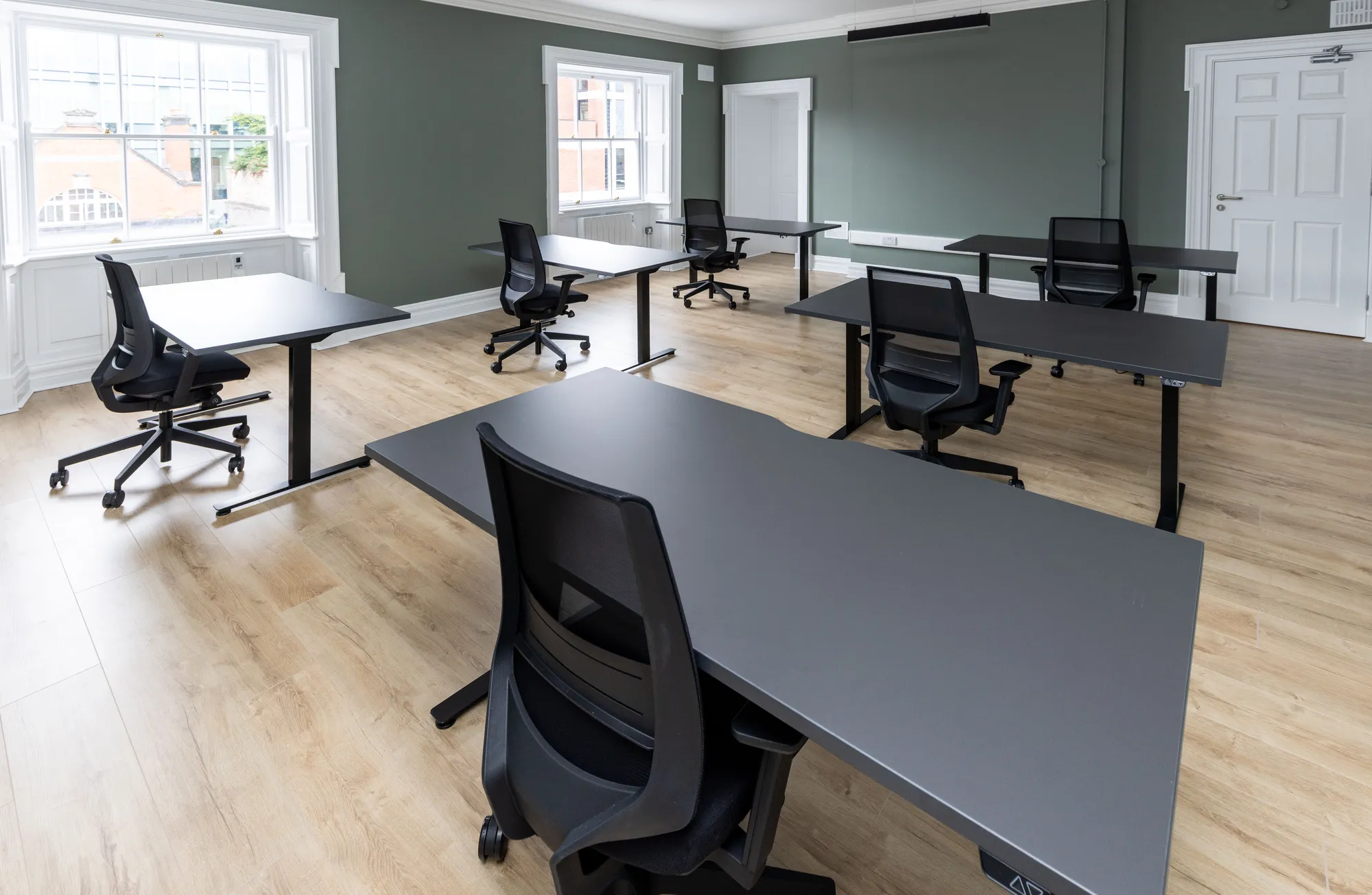 A private office with sit-stand desks and sage green walls