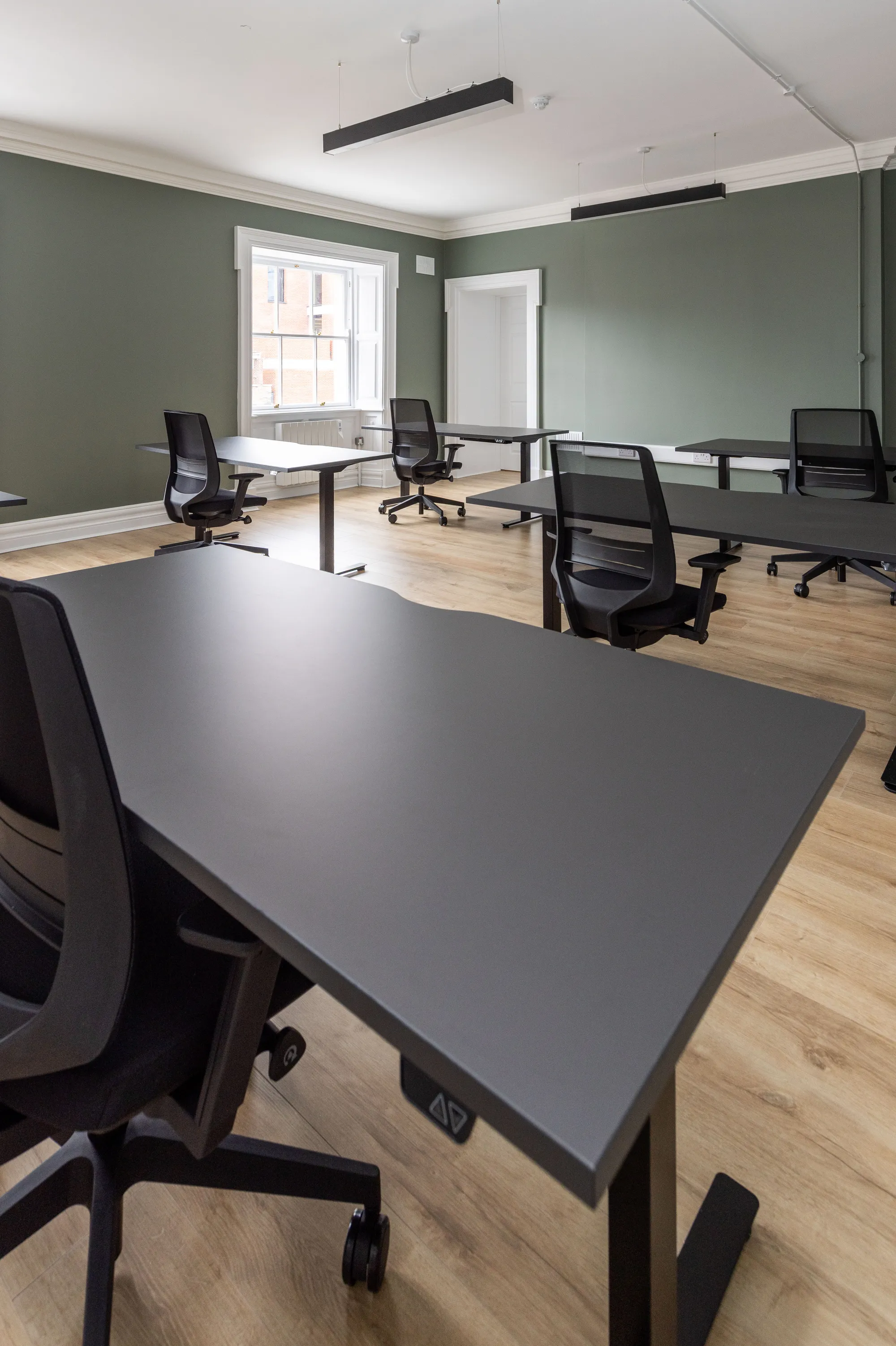 A sit-stand desk in a sage green office