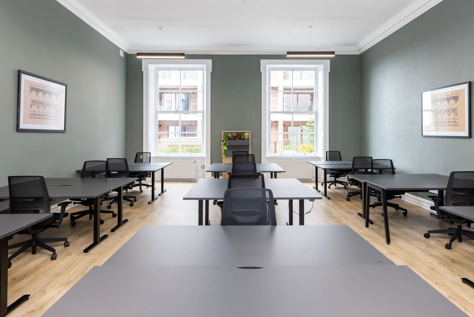 A long office with rows of desks and framed prints